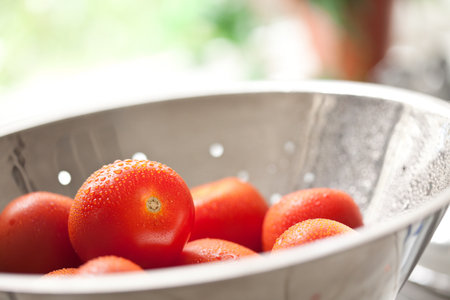 Macro of Fresh, Vibrant Roma Tomatoes in Colander with Water Drops Abstract.の写真素材