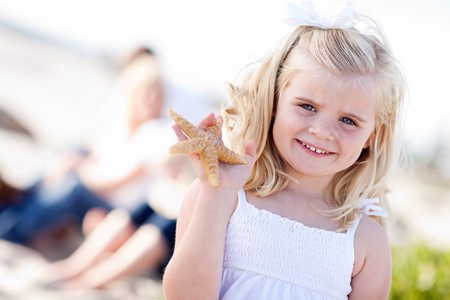 Adorable Little Blonde Girl with Starfish at The Beach.の写真素材
