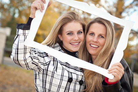 Pretty Mother and Daughter Portrait with Picture Frame in the Park on a Fall Day.の写真素材