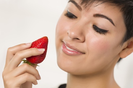 Pretty Hispanic Woman Holding Strawberry in Her Kitchen.の写真素材