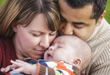 Happy Mixed Race Parents Hugging Their Son in the Park.