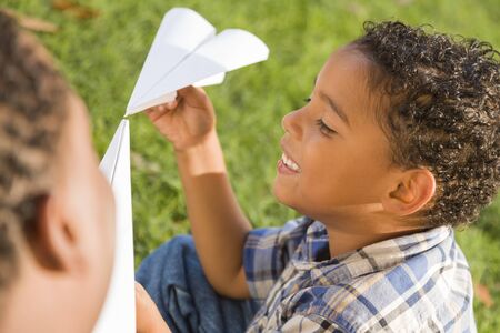 Happy Mixed Race Father and Son Playing with Paper Airplanes in the Park.の写真素材