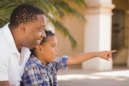 Happy African American Father and Mixed Race Son Pointing in the Park.の写真素材