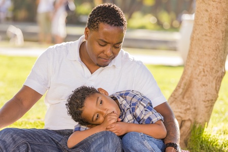 African American Father Worried About His Mixed Race Son as They Sit in the Park.の写真素材