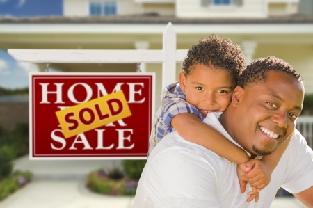 Happy Mixed Race Father and Son In Front of Sold Real Estate Sign and New House.の写真素材