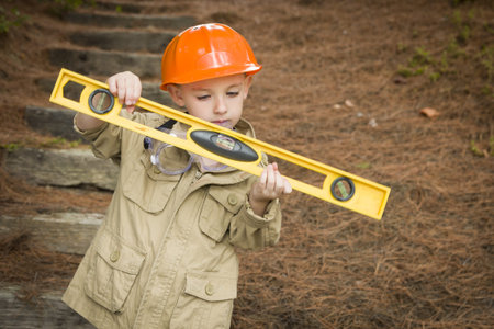 Happy Adorable Child Boy with Level, Hard Hat and Goggles Playing Handyman Outside.