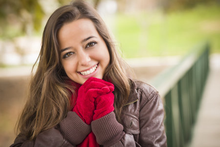Pretty Festive Smiling Woman Portrait Wearing a Red Scarf and Mittens Outside.