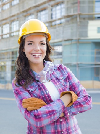 Portrait of Young Attractive Female Construction Worker Wearing Gloves, Hard Hat and Protective Goggles at Construction Site.の写真素材
