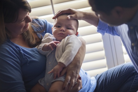 Happy Mixed Race Couple Enjoying Their Newborn Son In The Light of The Window.の写真素材