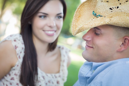 Happy Mixed Race Romantic Couple with Cowboy Hat Flirting in the Park.の写真素材