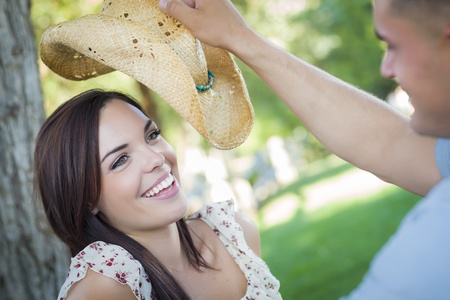 Happy Mixed Race Romantic Couple with Cowboy Hat Flirting in the Park.の写真素材