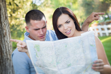 Lost and Confused Mixed Race Couple Looking Over A Map Outside Together.