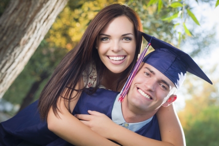 Happy Male Graduate in Cap and Gown and Pretty Girl Celebrate Outside.の写真素材