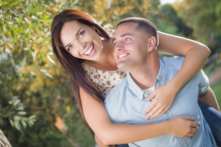 Happy Mixed Race Romantic Couple Piggyback Portrait in the Park.の写真素材