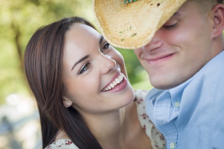 Happy Mixed Race Romantic Couple with Cowboy Hat Flirting in the Park.の写真素材