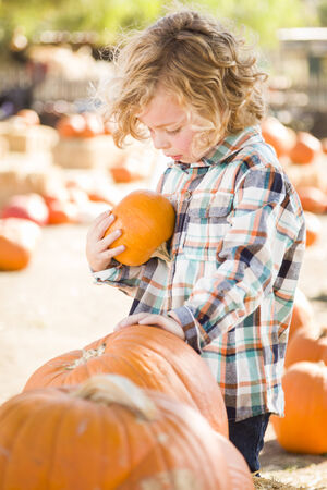 Adorable Little Boy Sitting and Holding His Pumpkin in a Rustic Ranch Setting at the Pumpkin Patch.
の写真素材