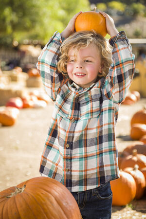 Adorable Little Boy Sitting and Holding His Pumpkin in a Rustic Ranch Setting at the Pumpkin Patch.
の写真素材