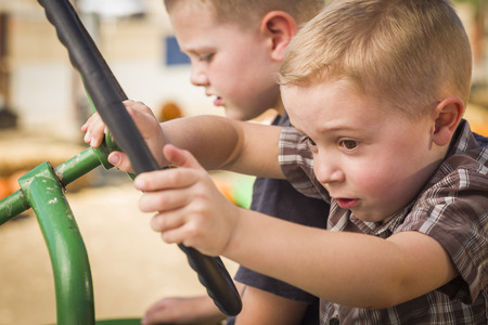 Adorable Young Boys Playing on an Old Tractor in a Rustic Outdoor Fall Setting.の写真素材
