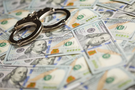 Handcuffs Laying on Newly Designed U.S. One Hundred Dollar Bills.の写真素材