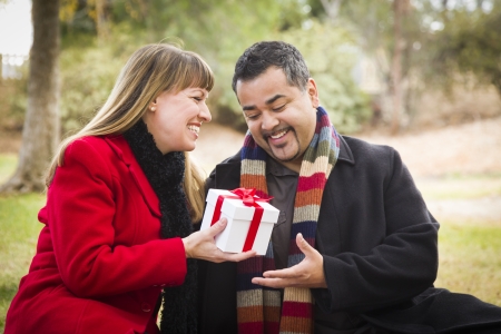 Young Attractive Mixed Race Couple Sharing Christmas or Valentines Day Gift in the Park の写真素材