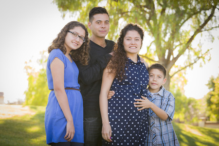 Happy Attractive Hispanic Family With Their Pregnant Mother Outdoors At the Park.の写真素材