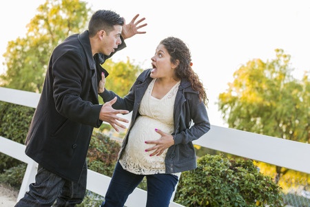 Stunned and Excited Pregnant Woman and Husband with Hand on Belly Outside.の写真素材