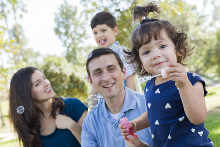 Cute Young Baby Girl Blowing Bubbles with Her Family in the Park.の写真素材