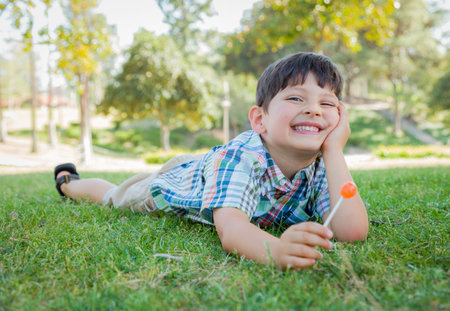 Handsome Young Boy Enjoying His Lollipop Outdoors on the Grass.の写真素材