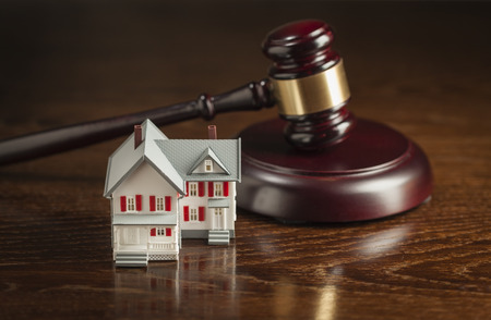 Gavel and Small Model House on Wooden Table.の写真素材
