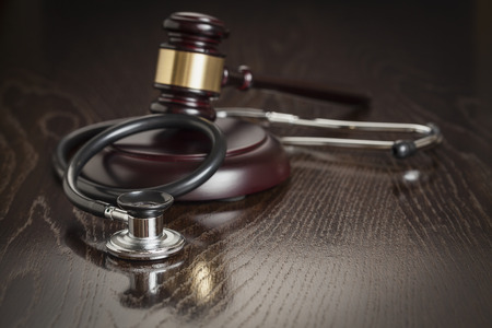 Gavel and Stethoscope on Reflective Wooden Table.の写真素材