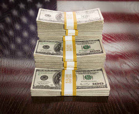Thousands of Dollars Stacked with Reflection of American Flag on Wooden Table.の写真素材