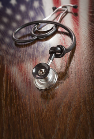 Knotted Stethoscope with American Flag Reflection on Wooden Table.の写真素材