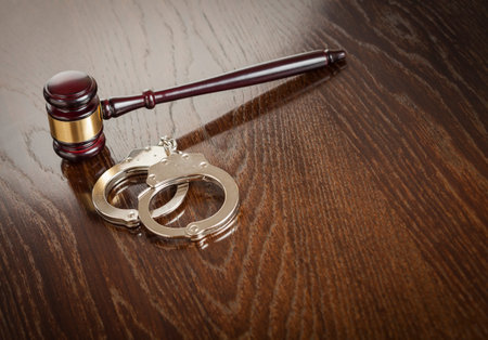 Gavel and Pair of Handcuffs on Wooden Table.の写真素材