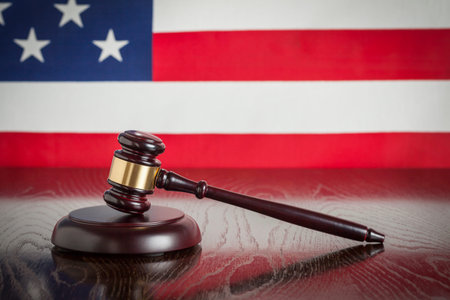 Wooden Gavel Resting on American Flag Reflecting Table.