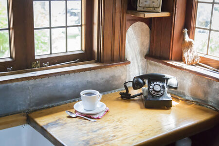 Classic Antique Phone and Cup of Coffee in Old Kitchen Setting.の写真素材