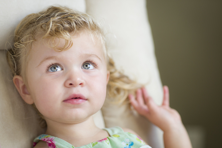 Adorable Blonde Haired and Blue Eyed Little Girl Sitting in Chair.の写真素材