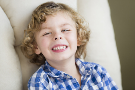 Cute Blonde Boy Smiling for Portrait Sitting in Chair.の写真素材