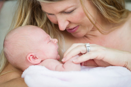 Young Caucasian Beautiful Mother Holding Her Precious Newborn Baby Girl.