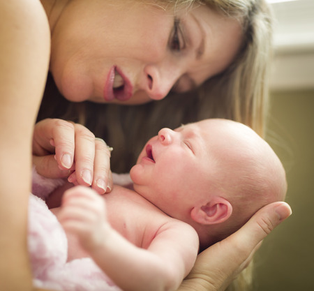 Young Caucasian Beautiful Mother Holding Her Precious Newborn Baby Girl.の写真素材