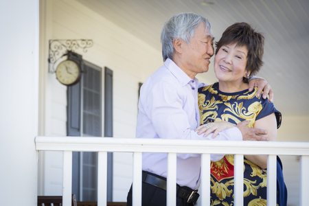 Attractive Happy Chinese Couple Enjoying Their House Outside.の写真素材