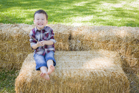 Cute Young Mixed Race Boy Having Fun on Hay Bale Outside.の写真素材