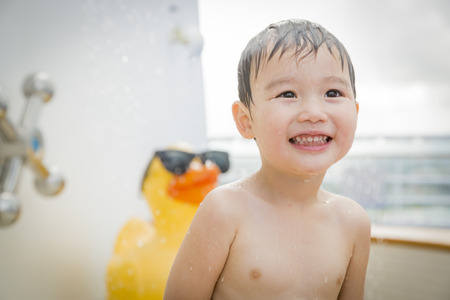 Mixed Race Boy Having Fun at the Water Park with Large Rubber Duck in the Background.の写真素材