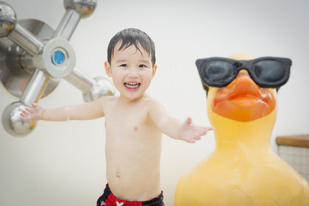 Mixed Race Boy Having Fun at the Water Park with Large Rubber Duck in the Background.の写真素材