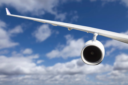 Large Airplane Wing Against Blue Sky and Clouds.