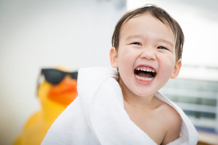 Mixed Race Boy Having Fun at the Water Park with Large Rubber Duck in the Background.