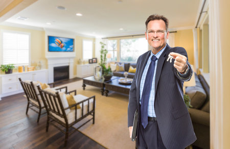 Smiling Male Real Estate Agent Handing Over Keys Standing in Beautiful Living Room.