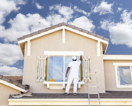 Busy House Painter Painting the Trim And Shutters of A Home. Busy House Painter Painting the Trim And Shutters of A Home.