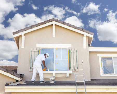 Busy House Painter Painting the Trim And Shutters of A Home. Busy House Painter Painting the Trim And Shutters of A Home.