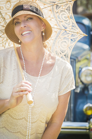 Beautiful 1920s Dressed Girl with Parasol Near Vintage Car Portrait.の写真素材