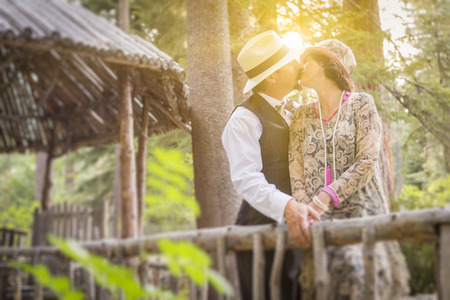 Attractive 1920s Dressed Romantic Couple Kissing on Wooden Bridge.の写真素材